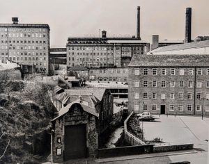 Black and white photo looking at former mill buildings by an industrialised river in Halifax.