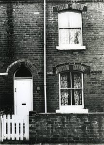 A black and white photo showing a small, stone-built terrace house