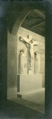 Sepia photo taken through an archway, showing a sculpture of Jesus on the cross with two saints beside him.