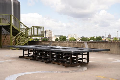 A large table-like sculpture, displayed on a concrete rooftop space.