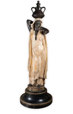 Statue of an African woman stading with her arms behind her head, carrying a jug on top of her head. The woman is sculptued in onyx, her floor-length dress in marble, and the jug in bronze.