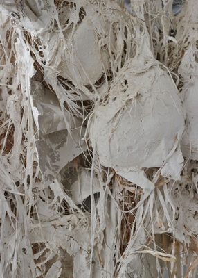Close up view of tangled, matted fibres and fabric, painted white.