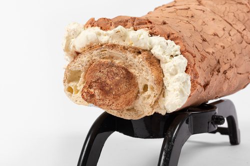 A sculpture of a sausage in a baguette on a black stand