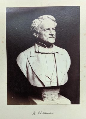 Black and white photo of a portrait bust of a man wearing a suit and bow tie.