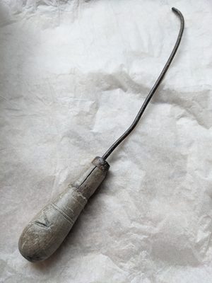 A modelling tool with a wooden handle and a long, curved piece of metal.
