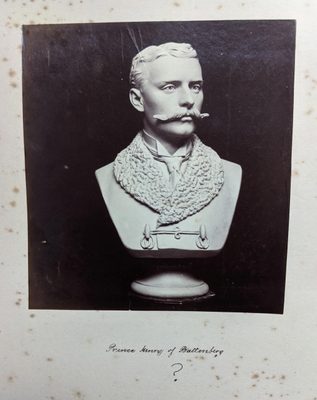 Black and white photo of a portrait bust of a formally-dressed man with a large moustache.