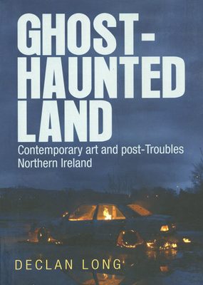 Cover of the book 'Ghost-haunted land : contemporary art and post-Troubles Northern Ireland', showing a burn out car, still slowly burning, at night.