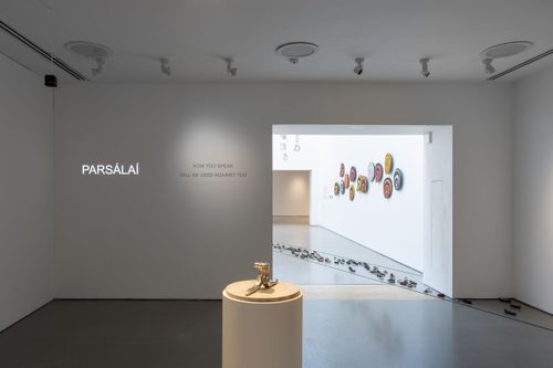 Installation view of 'The Weight of Words' exhibition, showing works in Gallery 3 by Caroline Bergvall with Ciarán Ó Meachair, Slavs and Tatars, and Issam Kourbaj. Work by Emma Hart is also visible through the doorway leading to Gallery 2.