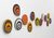 Photo of Emma Hart's 'Good Vibrations': 13 handmade ceramic circles, each painted in a bullseye pattern in different colours: bands of yellow, orange, red, or white alternating with black.