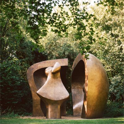A colour photo of Henry Moore's bronze sculpture 'Large Figure in a Shelter' 1985-86 sited in a woodland clearing