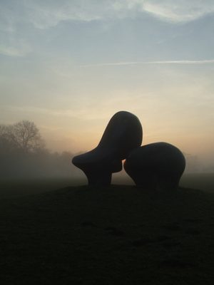 A silhouetted photo of Henry Moore's Sheep Piece at a misty sunset