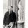 Henry Moore, a young man dressed in a suit and holding a cigarette, standing next to an abstract stone sculpture of a nude standing woman. The sculpture is around 4ft tall, but stands higher than Moore due to its placement on a narrow, striped pillar.
