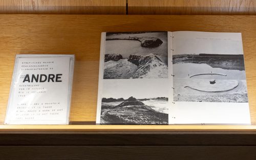 Shelf displaying two books; one has title 'Andre', while the other is open, showing black and white photos of 'land art' sculptures.