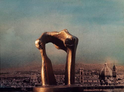 A small bronze model of 'The Arch' by Henry Moore, photographed against an image of the Florence skyline, so that the model appears larger than it really is.