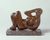 A photo of a small reclining figure sculpture in a reddish brown stone