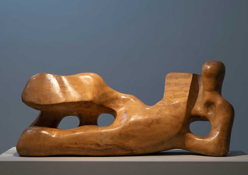 A carved wooden sculpture of a reclining figure by Henry Moore.