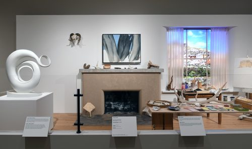 A recreation of Georgia O'Keefe's studio, with a fireplace and window surrounded by sculptures, paintings and found material such as bones and antlers.