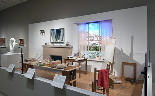 A recreation of Georgia O'Keefe's studio, with a fireplace and window surrounded by sculptures, paintings and found material such as bones and antlers.