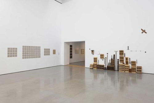 A white gallery space with a high ceiling, showing many of Roger Ackling's works.