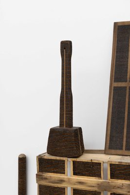 A wooden hammer resting on top of a wooden crate. Both have been striped with burned, horizontal lines, made using a magnifying glass and the sun.