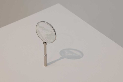 A tiny, transparent drawing of a glacier on the glass of a watch face in a circular frame, standing on a plinth. It looks similar to a small magnifying glass.