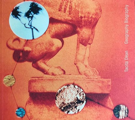 Cover of the book 'Tacita Dean: Geography Biography', showing a close-up, cropped photo of a stone sculpture of a sphinx, tinted orange.